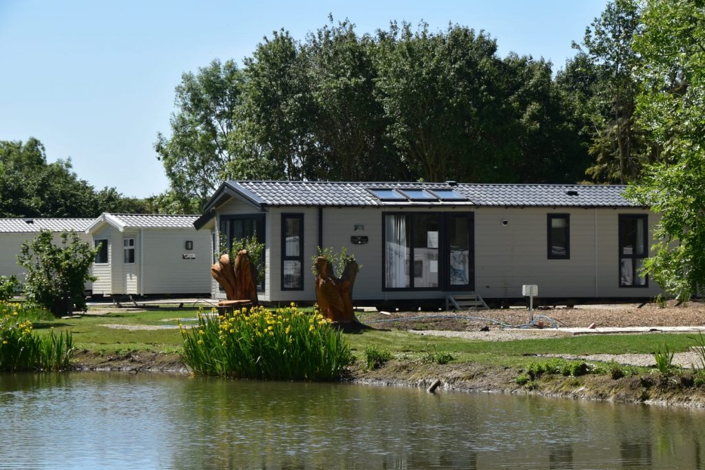 A static caravan at Brickyard Lakes on the water’s edge, representing holiday homes with fishing lakes.
